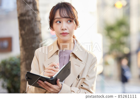 A woman writing a schedule in a notebook in the city A woman writing a schedule in a notebook in the city 85261111