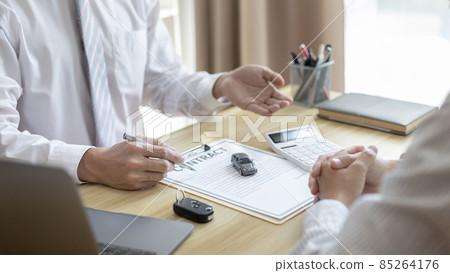 Selling cars, Car dealership or sales manager offers the sale of a car and explains the terms of signing a car purchase and insurance contract, Finance and after-sales service concept.  85264176