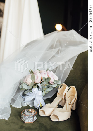 Wedding bouquet of white peonies, shoes and wedding rings on a wooden background 85264252