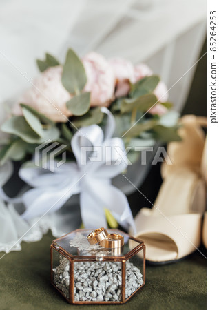 Wedding bouquet of white peonies, shoes and wedding rings on a wooden background 85264253