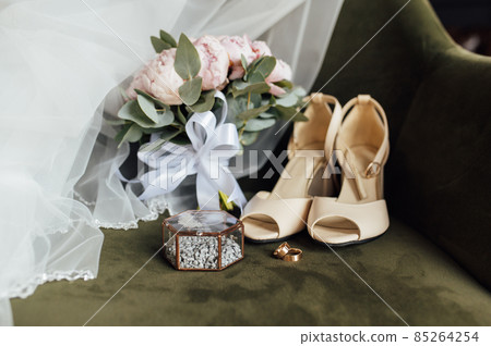 Wedding bouquet of white peonies, shoes and wedding rings on a wooden background 85264254