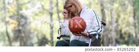 Disabled woman in wheelchair holding basketball ball and crying 85265202