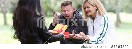 Woman giving gift in red box young couple in park 85265203