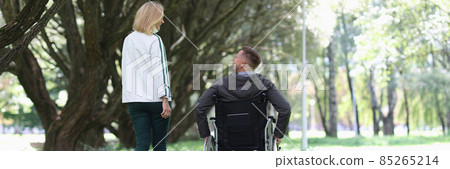 Man in wheelchair is walking in park with his girlfriend 85265214