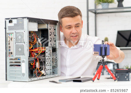 a man records a video lesson on computer repair or makes an online consultation. a man records a video lesson on computer repair or makes an online consultation. 85265987
