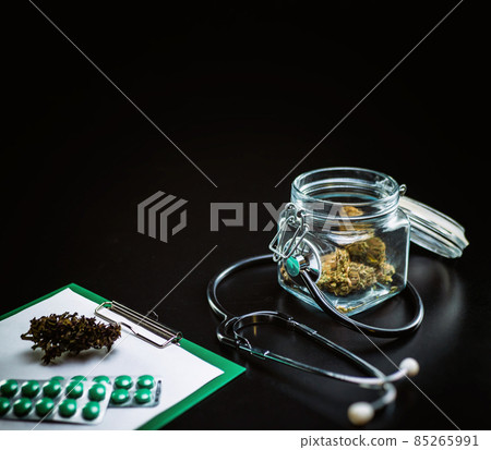 Dry medical cannabis in a jar with a stethoscope on a black background Dry medical cannabis in a jar with a stethoscope on a black background 85265991