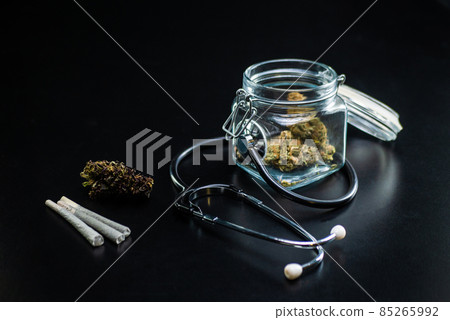 Dry medical cannabis in a jar with a stethoscope on a black background Dry medical cannabis in a jar with a stethoscope on a black background 85265992