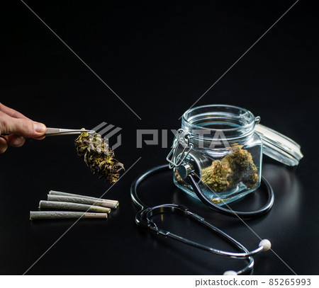 Dry medical cannabis in a jar with a stethoscope on a black background 85265993