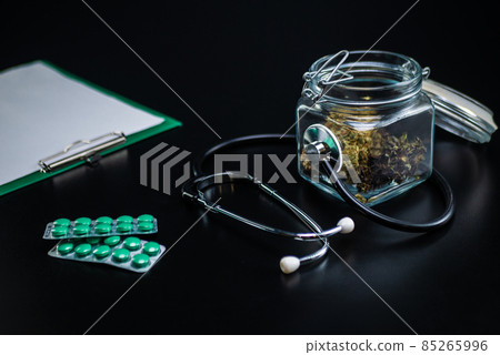 Dry medical cannabis in a jar with a stethoscope on a black background Dry medical cannabis in a jar with a stethoscope on a black background 85265996