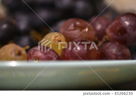 Juicy black grapes on a plate in the shade Juicy black grapes on a plate in the shade 85266230