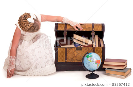 girl and a chest with books. little girl looking inside a trunk with surprise on white background 85267412