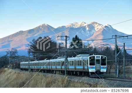 與北斗市長坂町的八岳在黃昏時沿著中央本線行駛的列車 85267696