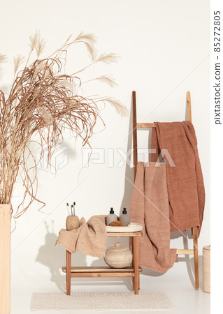 Natural waffle linen towels in earth tones on wood bench and towel ladder with bamboo toothbrushes, rattan baskets, and soap dispenser. Daily body care, spa and wellness zero waste bathroom concept Natural waffle linen towels in earth tones on wood bench and towel ladder with bamboo toothbrushes, rattan baskets, and soap dispenser. Daily body care, spa and wellness zero waste bathroom concept 85272805