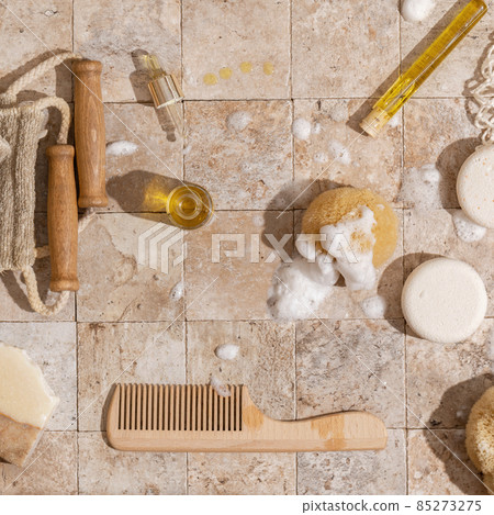 Zero waste bathroom accessories - soap, dry shampoo, exfoliating body strap, natural sea sponge with organic soap foam, wood brush, skin oil, mesh bag on earth toned stone tales top view direct Zero waste bathroom accessories - soap, dry shampoo, exfoliating body strap, natural sea sponge with organic soap foam, wood brush, skin oil, mesh bag on earth toned stone tales top view direct 85273275