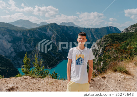 Guy traveler on the background The famous Piva Canyon with its fantastic reservoir. View of road above Piva Lake (Pivsko Jezero) in Montenegro. man looks at river Piva, Montenegro. 85273648