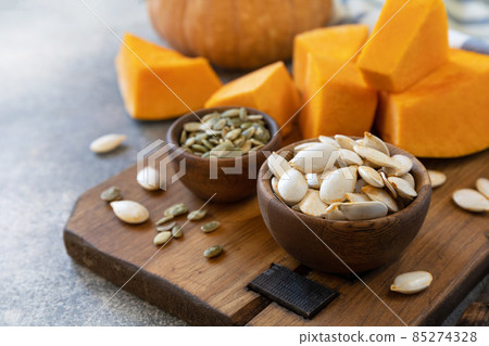 Raw superfoods pumpkin seeds after harvest. Pumpkin seeds in wooden bowl over gray stone background. Copy space. 85274328