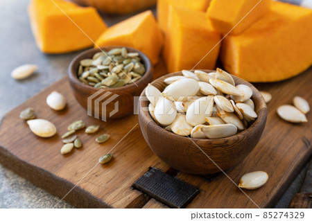 Raw superfoods pumpkin seeds after harvest. Pumpkin seeds in wooden bowl over gray stone background. 85274329