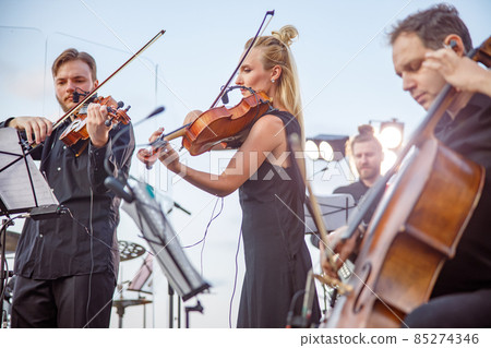 Musicians playing classical instrumental music on outdoor stage 85274346