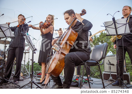 Musical ensemble playing classical music on outdoor stage 85274348