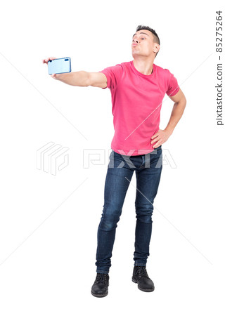 Joyful young male pouting lips and taking selfie against white background Joyful young male pouting lips and taking selfie against white background 85275264