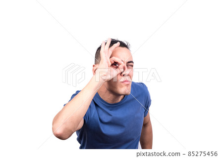 Man looking through a hole formed by his fingers Man looking through a hole formed by his fingers 85275456