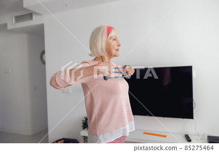 Senior woman stretching exercising equipment at cozy room Senior woman stretching exercising equipment at cozy room 85275464