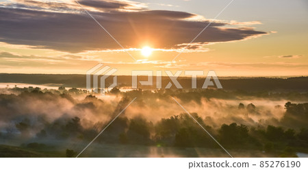 Sunrise of meadow with forest in sunlight and mist Sunrise of meadow with forest in sunlight and mist 85276190