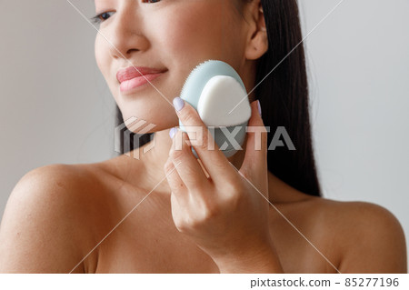Asian young woman using face massager in studio Asian young woman using face massager in studio 85277196
