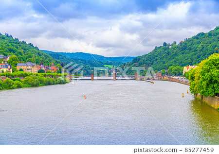 Neckar river with water dam and view of wooden green hills near Heidelberg town Neckar river with water dam and view of wooden green hills near Heidelberg town 85277459