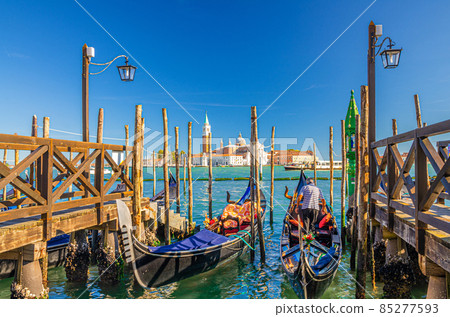 Gondolas moored docked at wooden pier in water of San Marco basin Gondolas moored docked at wooden pier in water of San Marco basin 85277593