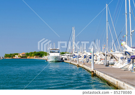 White yachts are moored on water of pier parking in marina port harbour of Sottomarina town White yachts are moored on water of pier parking in marina port harbour of Sottomarina town 85278080