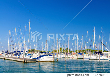 White yachts are moored on water of pier parking in marina port harbour of Sottomarina town White yachts are moored on water of pier parking in marina port harbour of Sottomarina town 85278082