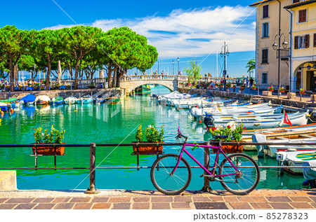 Bicycle bike near fence of old harbour Porto Vecchio with motor boats on turquoise water 85278323