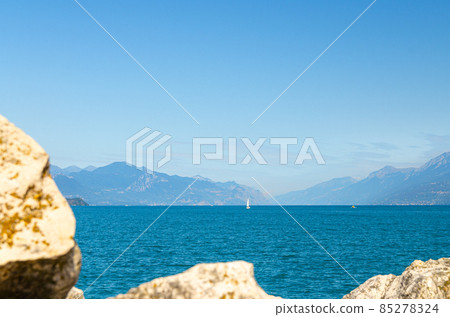 Small sailing yacht on Garda Lake azure water with Monte Baldo mountain range 85278324