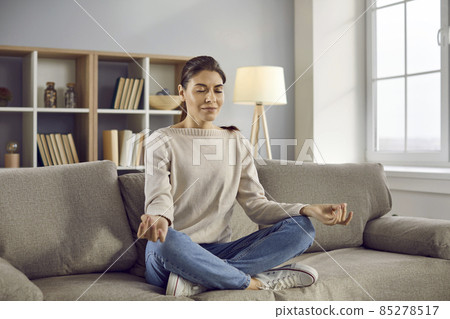 Calm millennial girl sit on sofa at home meditate practice yoga in mudra position. Relaxed young woman have meditation session indoors, relieve negative emotions breathe fresh air. Stress free. Calm millennial girl sit on sofa at home meditate practice yoga in mudra position. Relaxed young woman have meditation session indoors, relieve negative emotions breathe fresh air. Stress free. 85278517