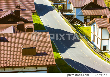 Aero view of brown tiled roofs with brick pipes of two-story houses paved street Aero view of brown tiled roofs with brick pipes of two-story houses paved street 85279344
