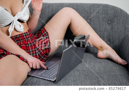 A young woman dressed in a schoolgirl costume is engaged in virtual sex on a laptop. The web model gets naked for the camera A young woman dressed in a schoolgirl costume is engaged in virtual sex on a laptop. The web model gets naked for the camera 85279817