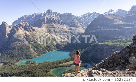 Female hiker enjoying beautiful view on alpine valley with glacial lakes surrounded by mountains Female hiker enjoying beautiful view on alpine valley with glacial lakes surrounded by mountains 85282184