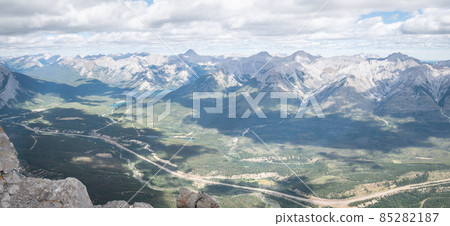 Wide panoramic view on green alpine valley with clouds casting shadows on it, Banff, Canada 85282187