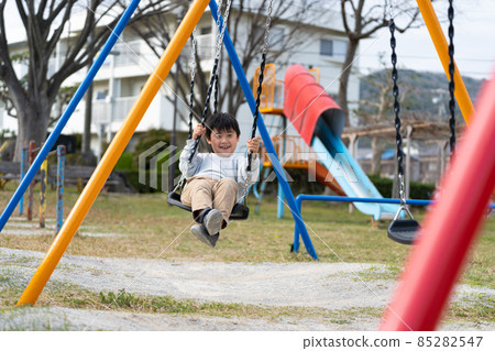 Boys elementary school students park swings play 85282547