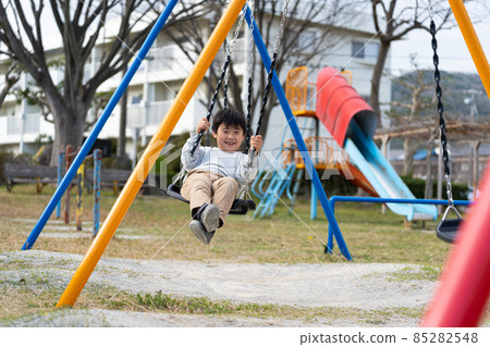 Boys elementary school students park swings play 85282548