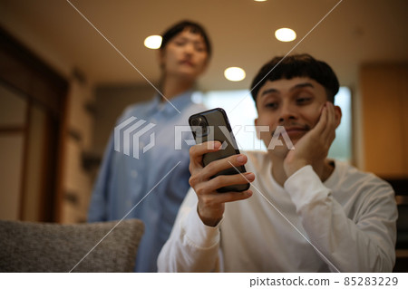 A man operating a smartphone and a suspicious woman 85283229