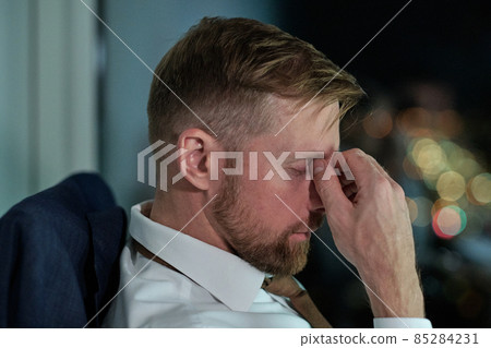 Side view of face of young tired businessman sitting by workplace Side view of face of young tired businessman sitting by workplace 85284231