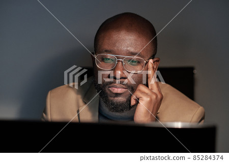 Serious young businessman in eyeglasses and formalwear sitting in front of computer monitor Serious young businessman in eyeglasses and formalwear sitting in front of computer monitor 85284374