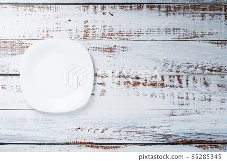 An empty round white plate on a blue wooden table. An empty round white plate on a blue wooden table. 85285345