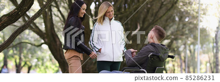 Man in wheelchair and laughing woman chatting in park 85286231