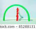 The curved pop tube stands leaning against the wall. Modern still life with antistress toy 85288131