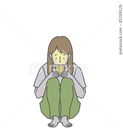 一個長發女人坐在黑暗中,她的膝蓋對著智能手機發瘋 一個長發女人坐在黑暗中,她的膝蓋對著智能手機發瘋 85289126