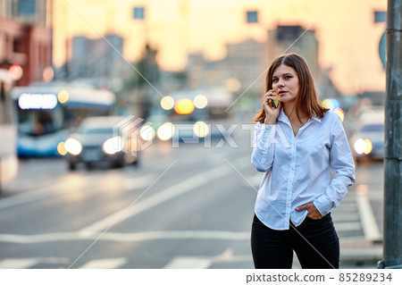Young woman is talking by handy on street with traffic. Young woman is talking by handy on street with traffic. 85289234