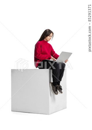 Full-length portrait of young cocentrated girl working on project, typing on laptop isolated over white background Full-length portrait of young cocentrated girl working on project, typing on laptop isolated over white background 85291371